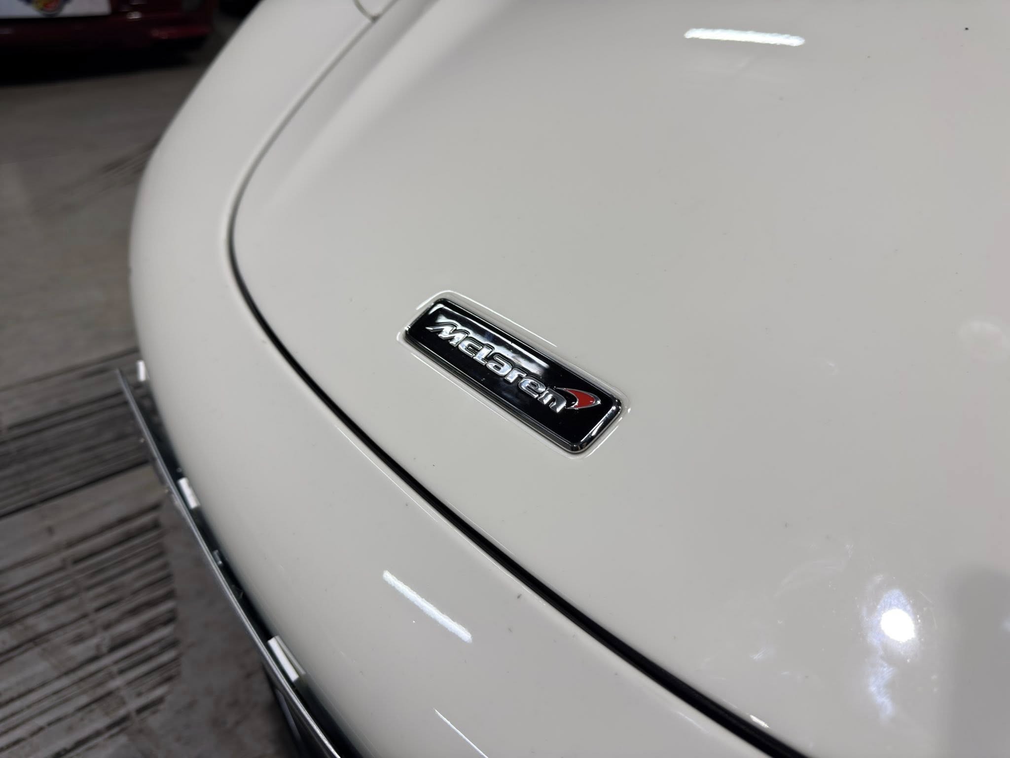 Close-up of a white car's rear with a chrome McLaren emblem.