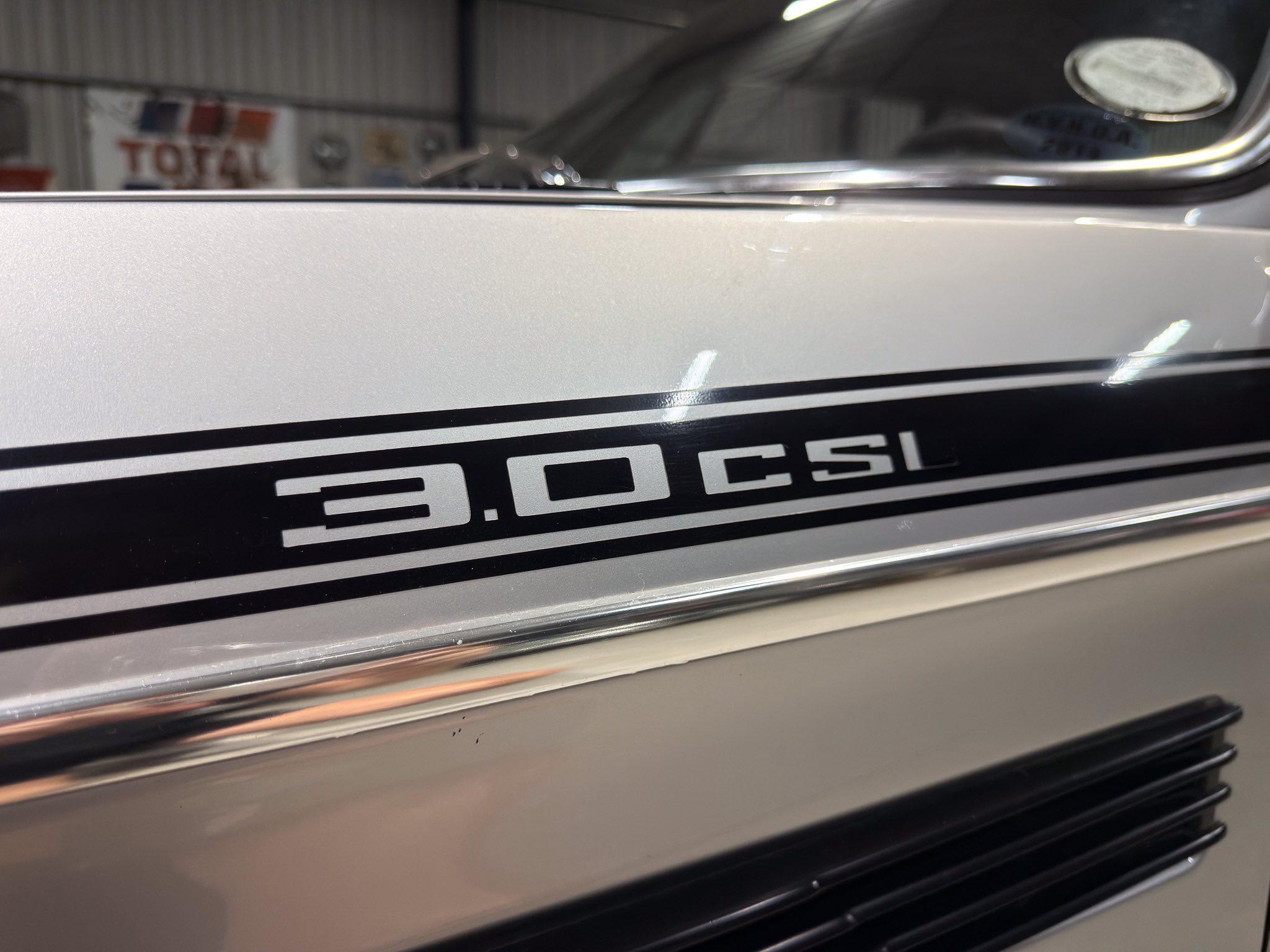 Close-up of a vintage car door in metallic gray with chrome trim and the '3.0 CSI' badge visible along the lower panel.