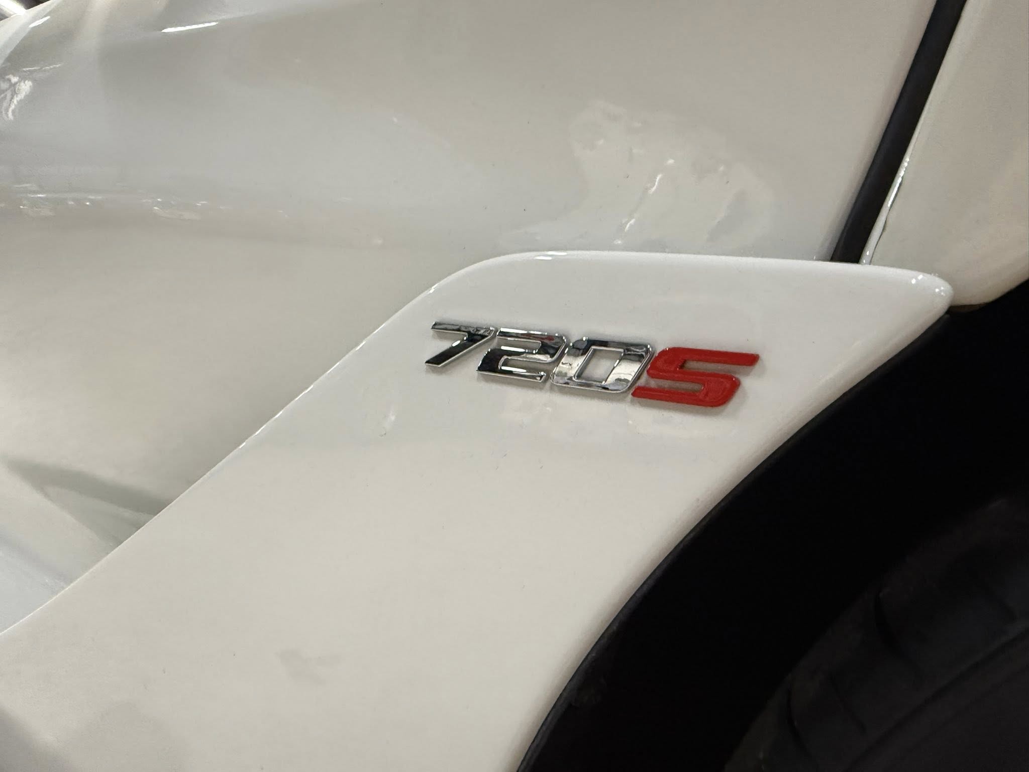 Close-up of chrome 720S badge on a white car body.