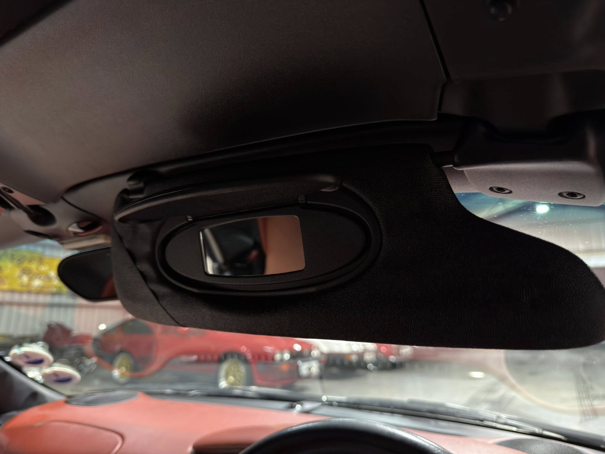 Close-up of a car’s overhead interior near the sun visor and rearview mirror.