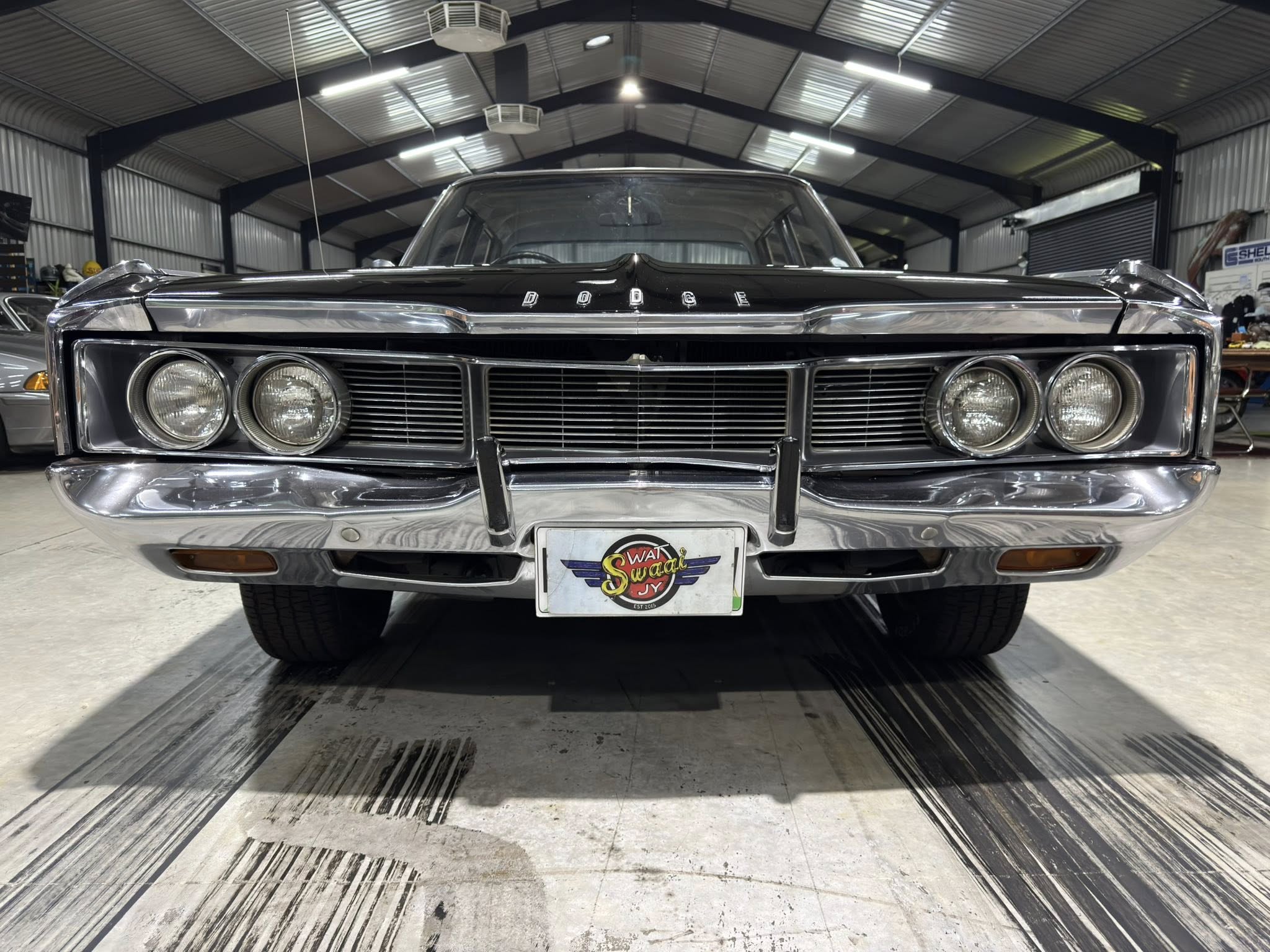 Front view of a vintage black Dodge with chrome grille and dual round headlights in a showroom setting