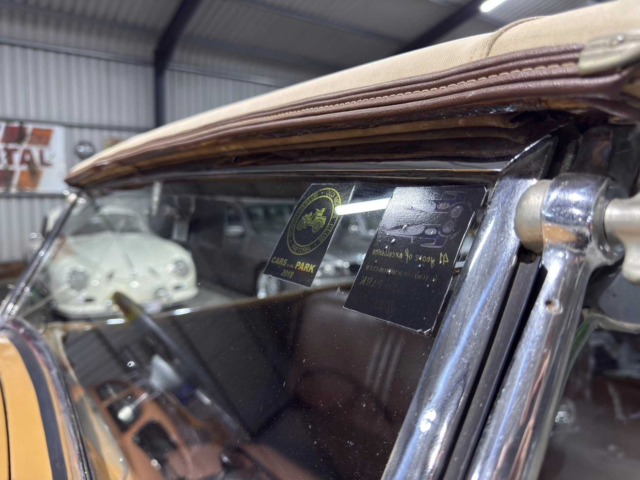 Close-up of brown leather trim and beige fabric folded over a car door, inside a workshop.