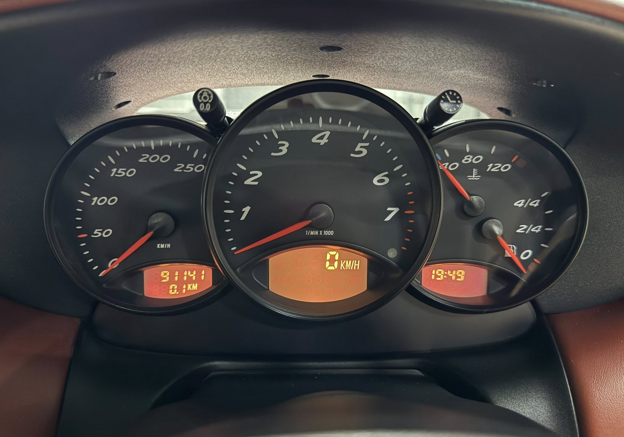 Close-up of a car instrument cluster with speedometer, tachometer, and digital readouts in orange LEDs
