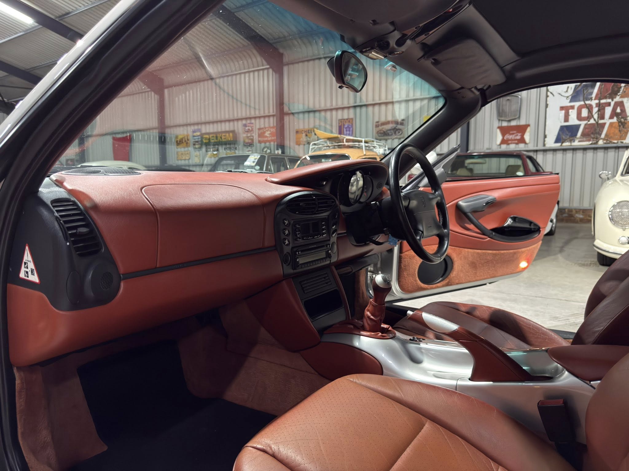Red leather car interior with center console, steering wheel, and passenger seat visible in a showroom.