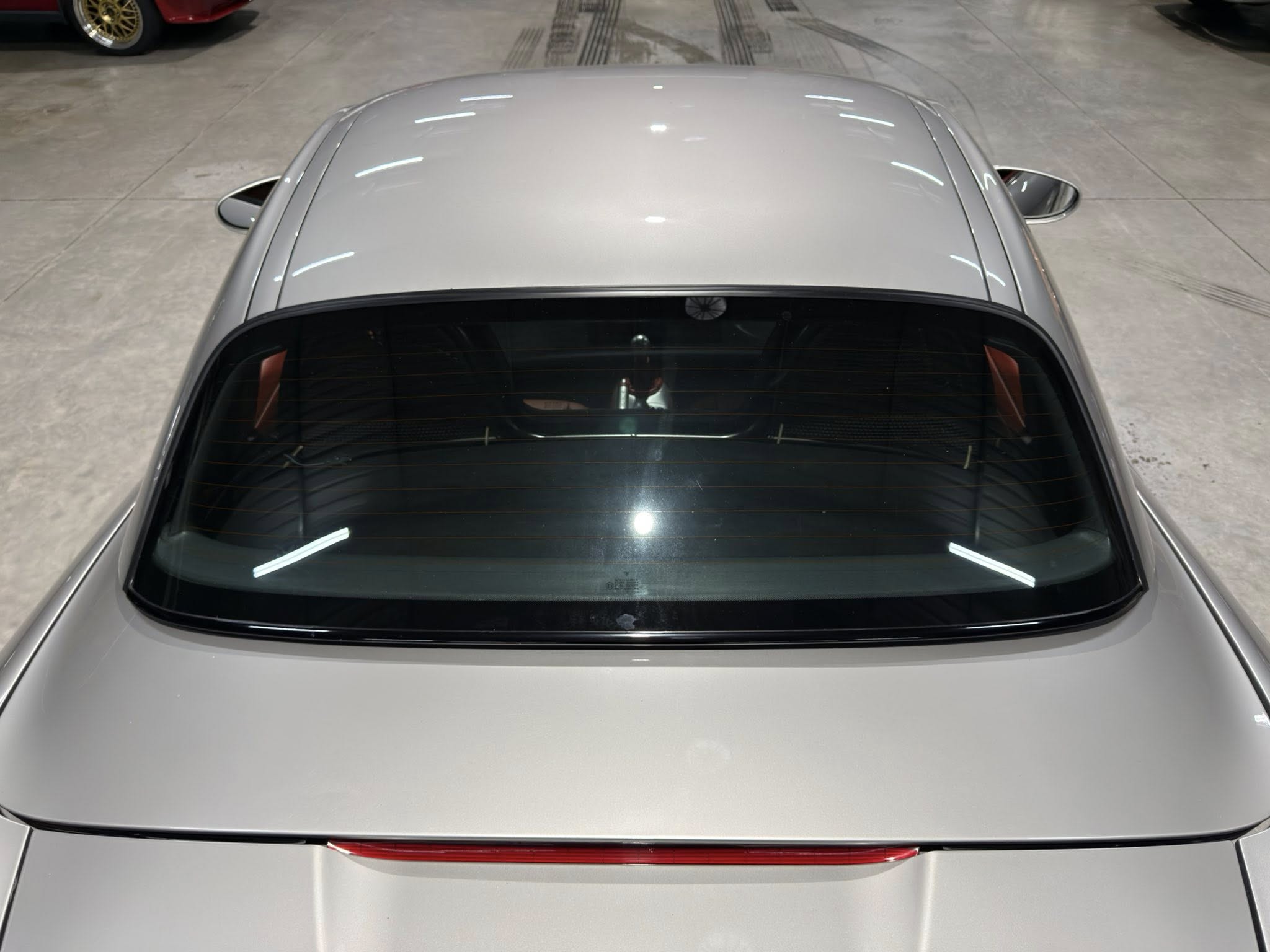 Top‑down view of a silver car, focusing on the rear window and roof in a showroom.