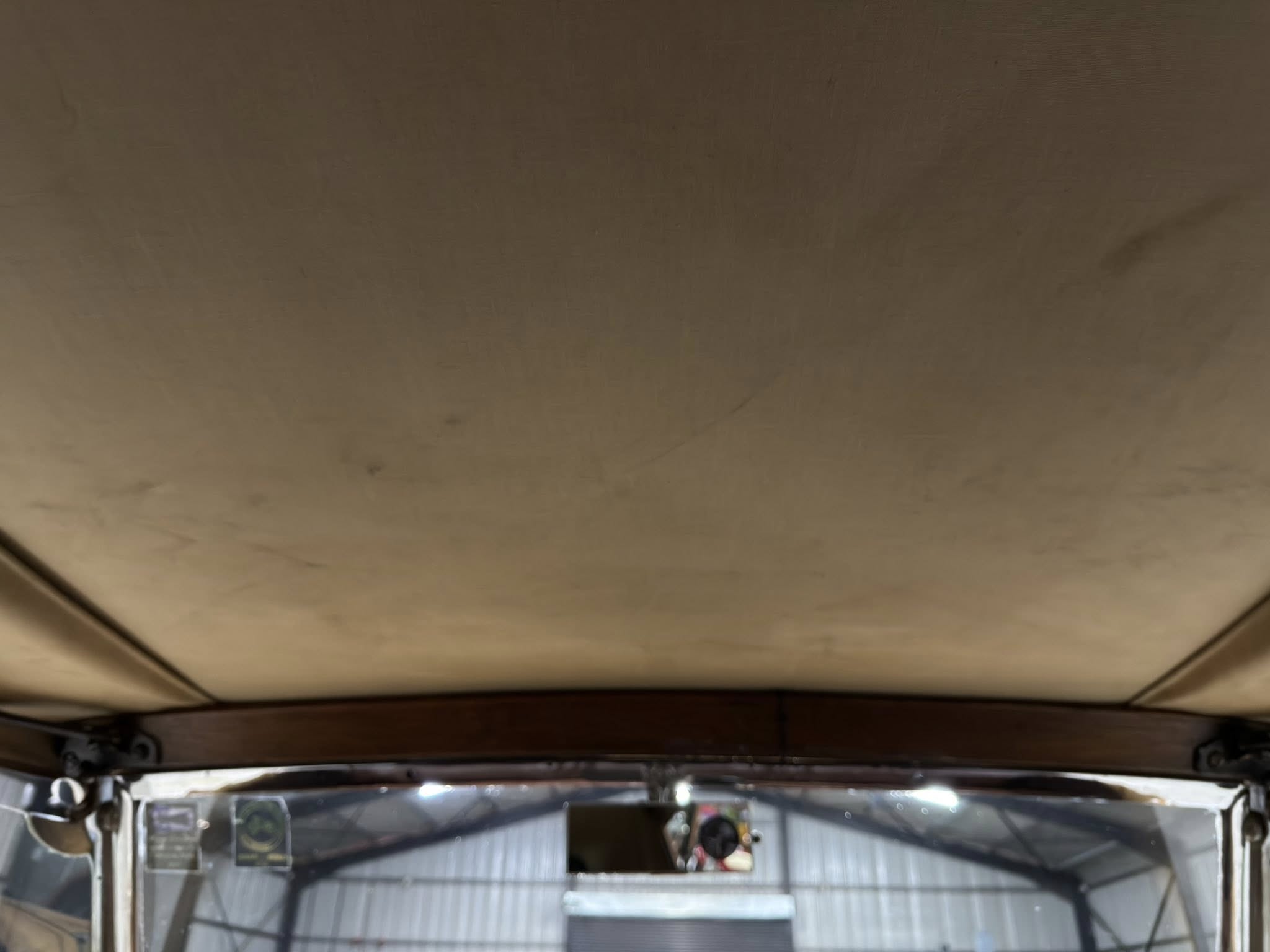 Interior of a vehicle showing a brown headliner and exposed metal framing in the cargo area.