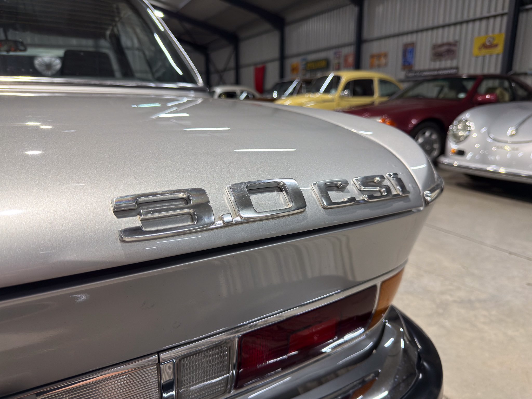 Close-up of the rear end of a silver Porsche in a showroom, with the 'PORS' trunk lettering visible.