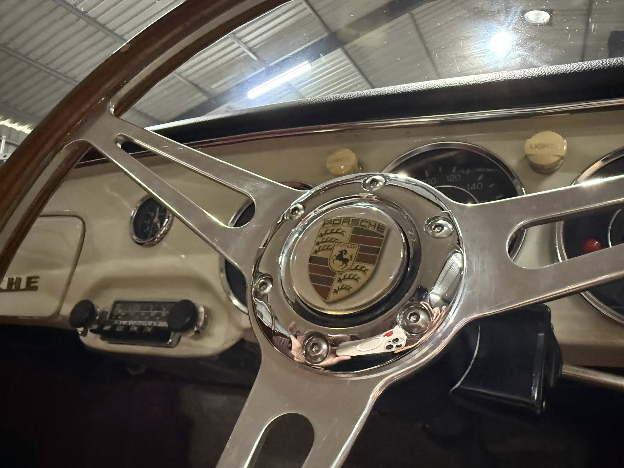 Close-up of a classic Porsche steering wheel and chrome dashboard accents.