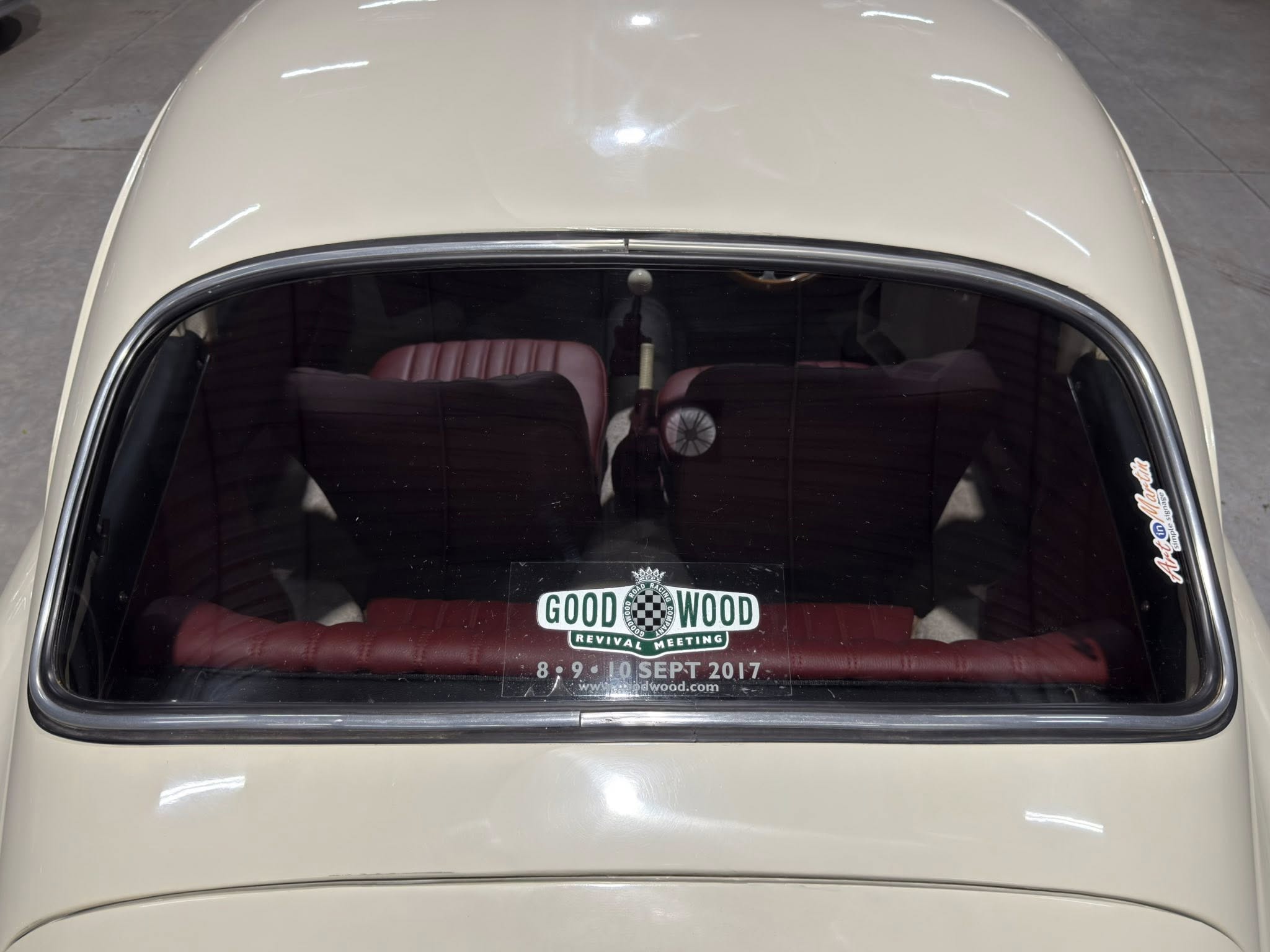 Top view of a beige vintage car with red interior; windshield displays a 'GOOD WOOD' decal and event dates 8-9 Sept 2017.
