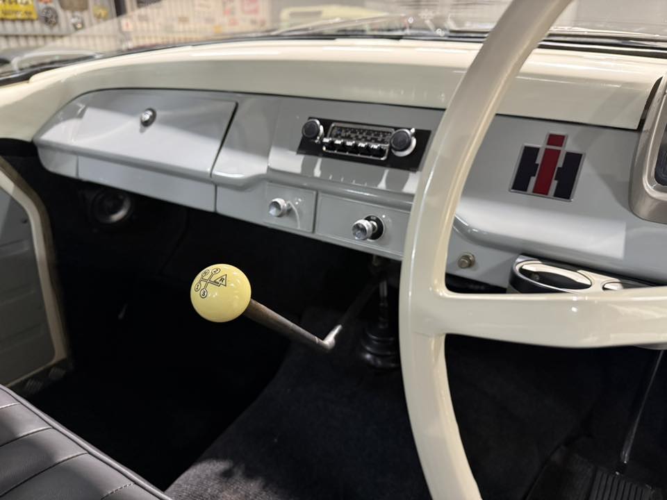 Vintage car interior showing a yellow knob gear shift, light gray dashboard, and steering wheel linked to a retro cockpit setting.