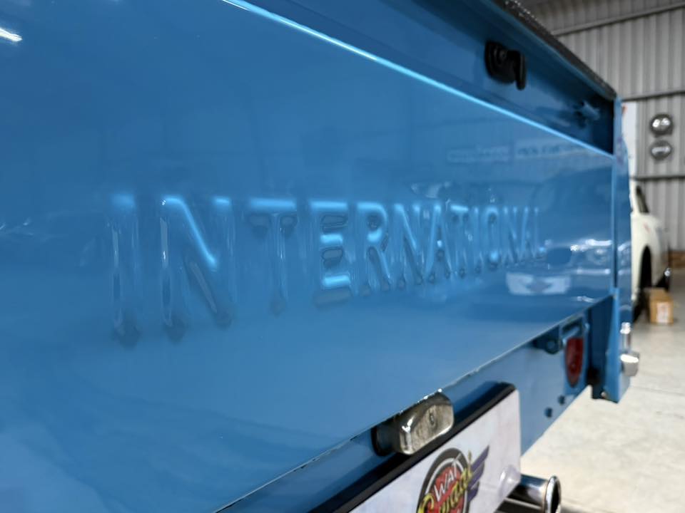 Close-up of a bright blue trailer side with embossed lettering, parked inside a warehouse/garage.