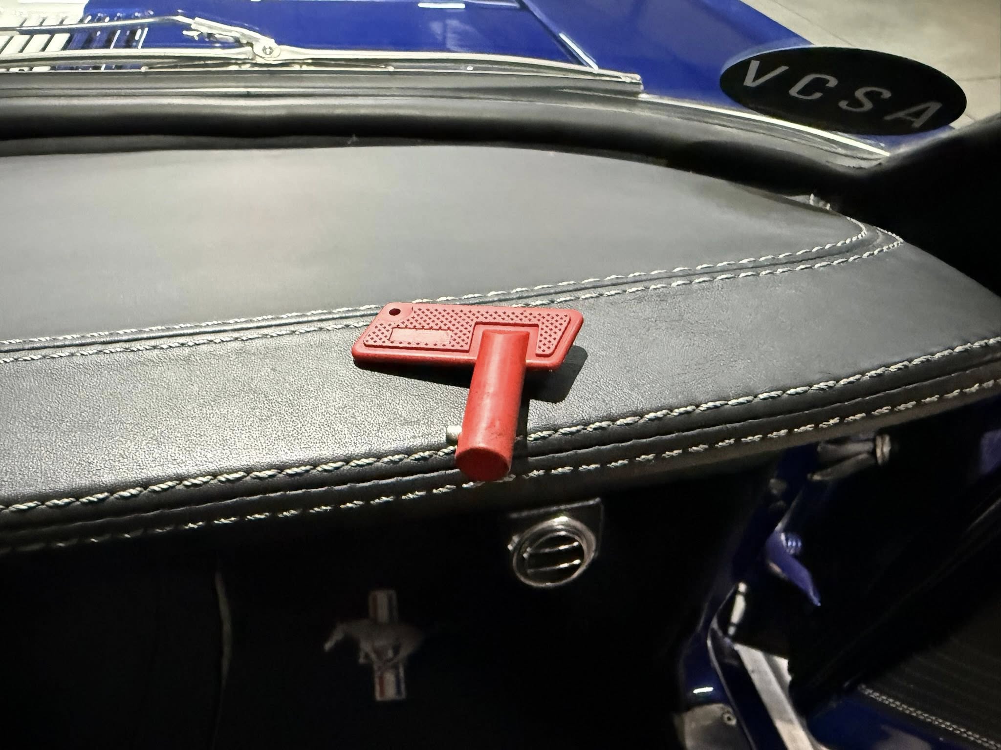 Close-up of a red toggle switch on a stitched black dashboard with blue exterior visible nearby.