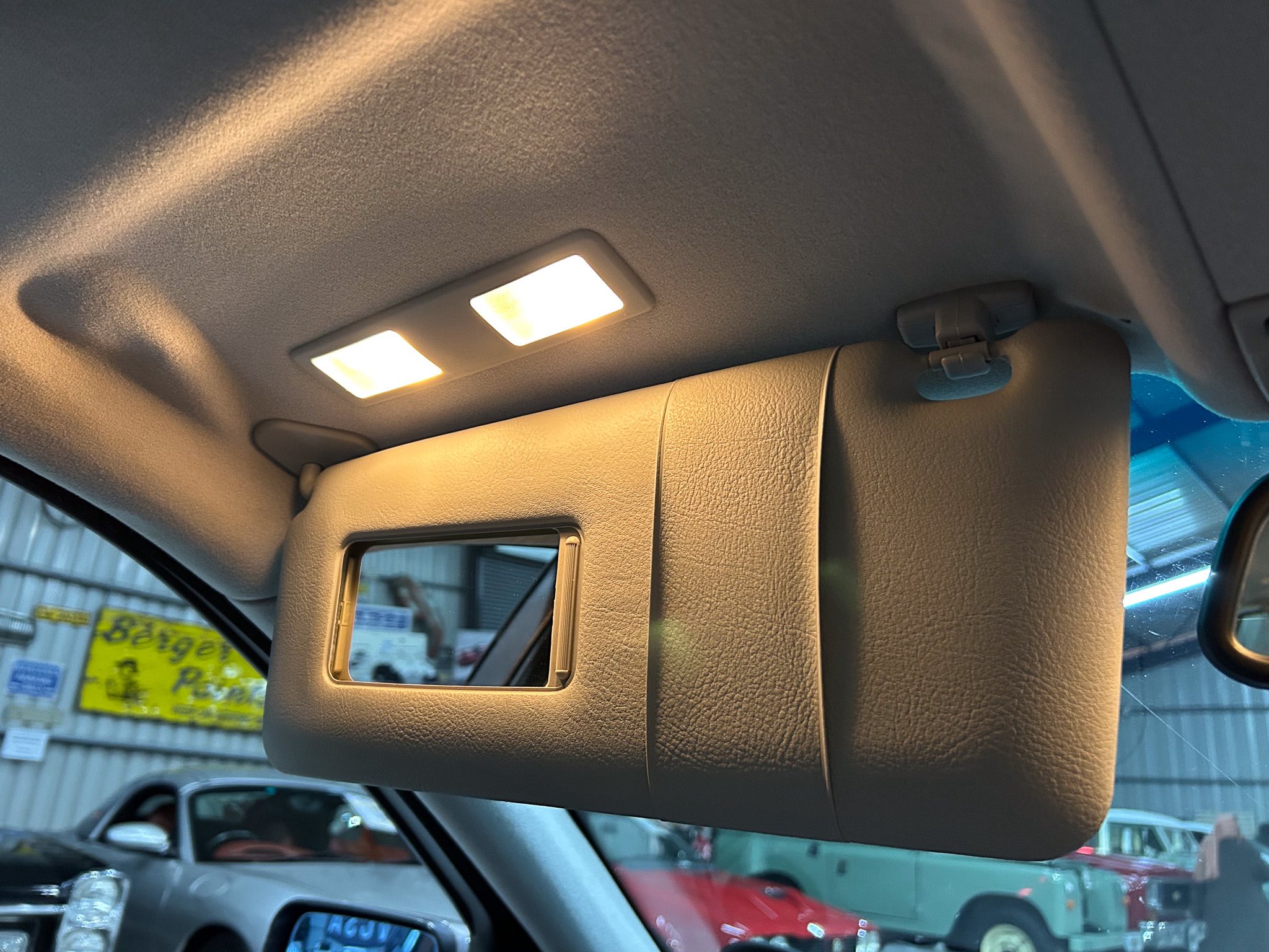 Interior of a car ceiling with two illuminated overhead lights.