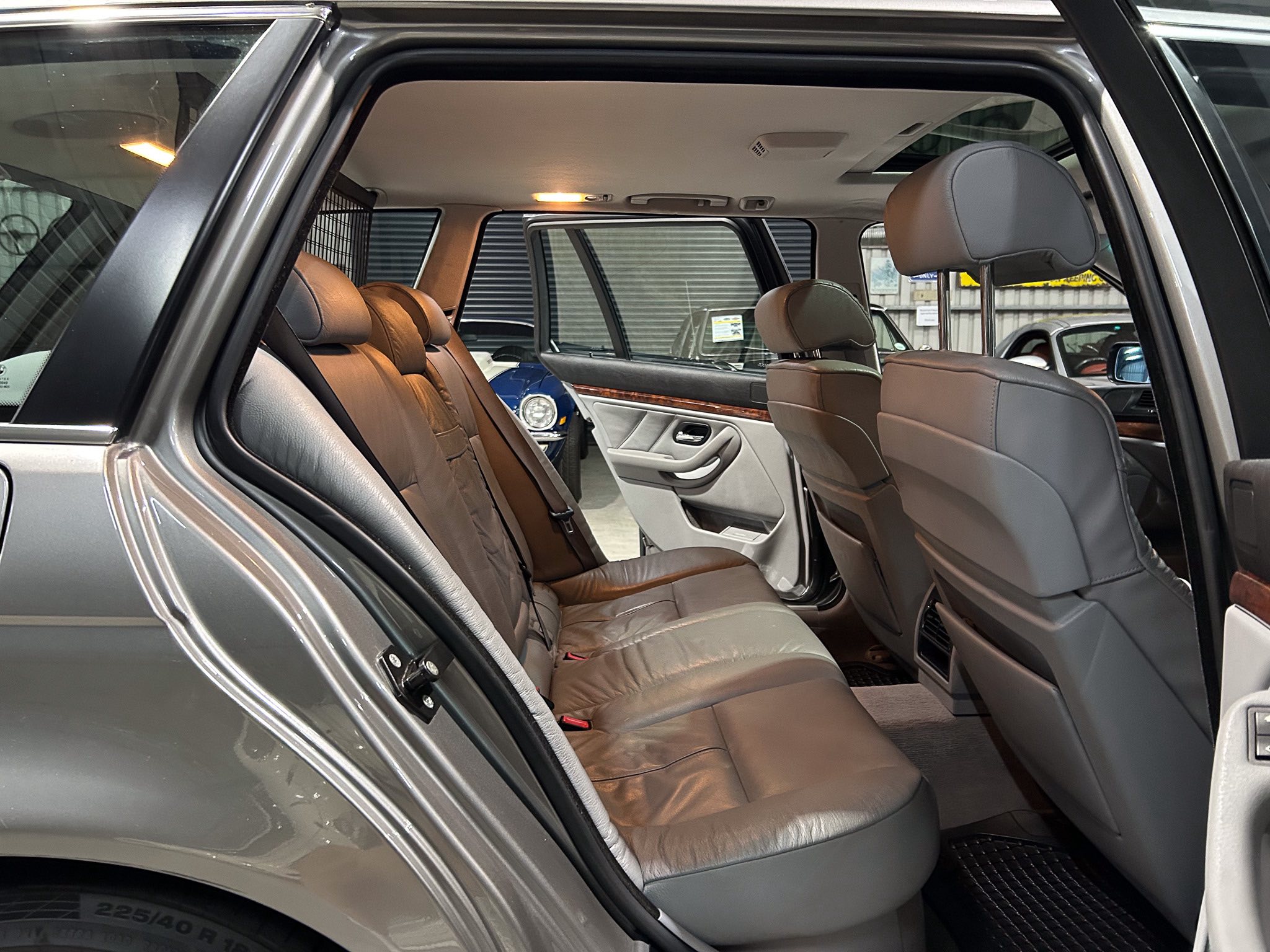 Back seat area of a gray SUV with tan leather seats, headrests, and wood trim along the door.
