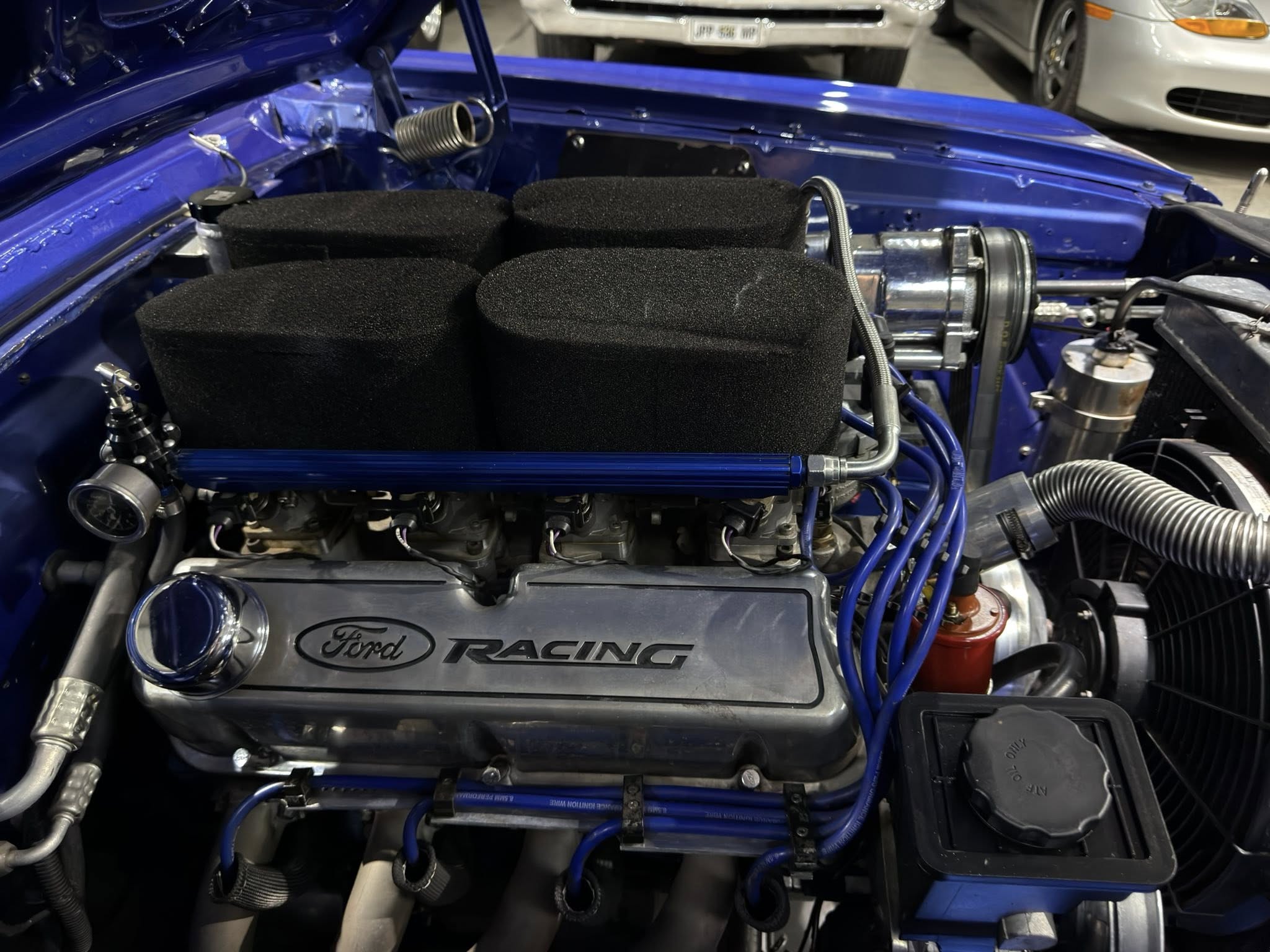 Blue Ford Racing engine bay with large black foam air filter housings and blue braided hoses visible under the hood's edge