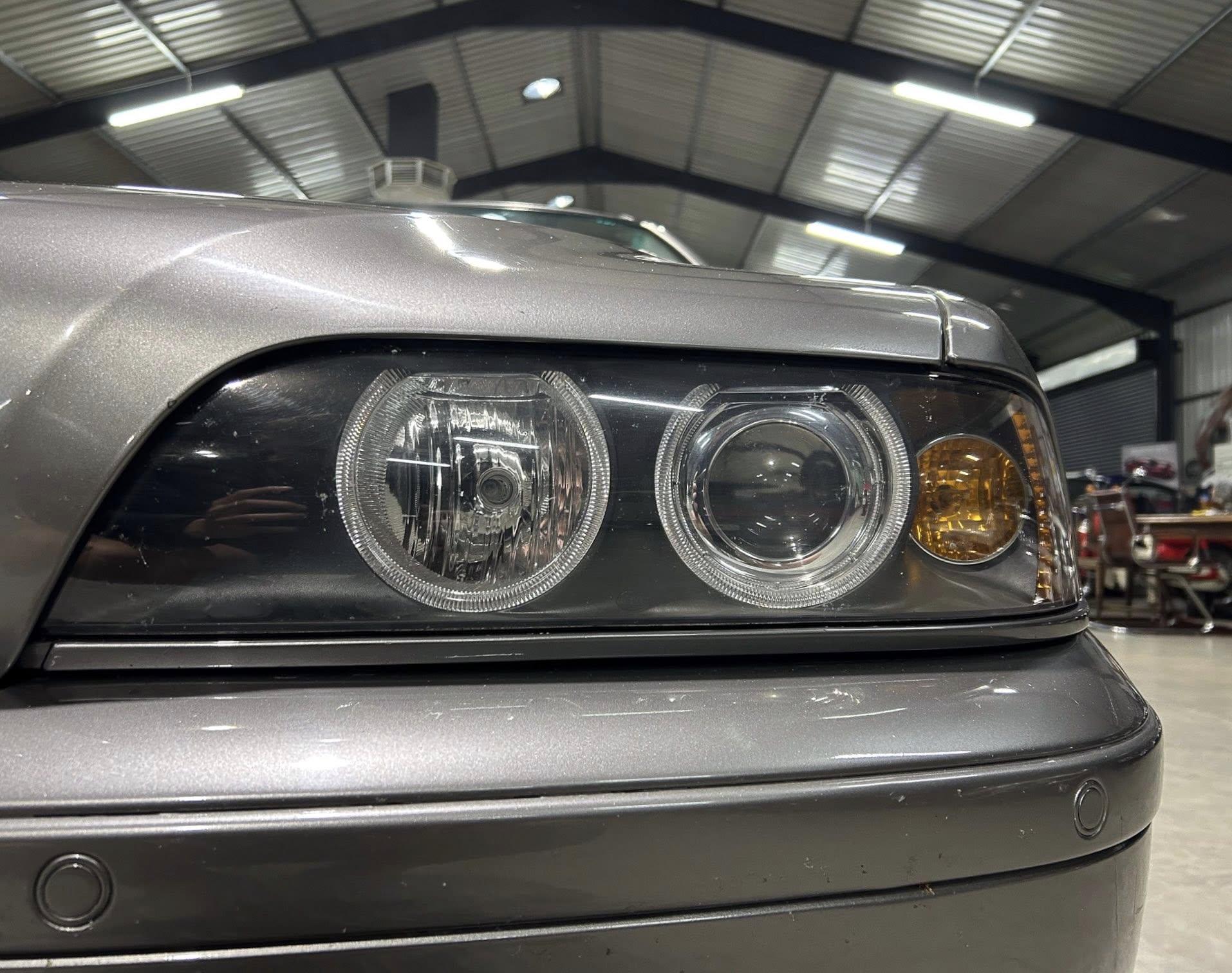 Close-up of a silver car's headlight assembly in a workshop or garage.