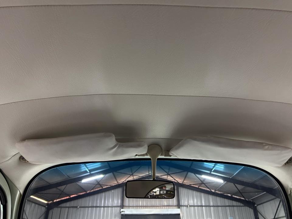 Interior of a car with both sun visors folded up and a center rearview mirror, seen through the windshield.