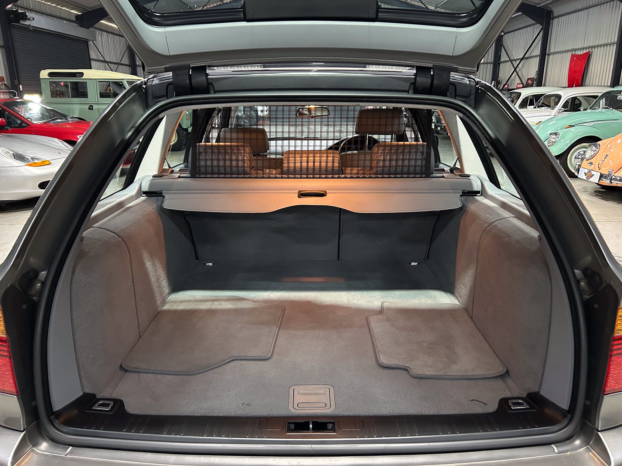 Open tailgate of an SUV showing a spacious cargo area with a metal grid divider behind the rear seats in a car showroom.