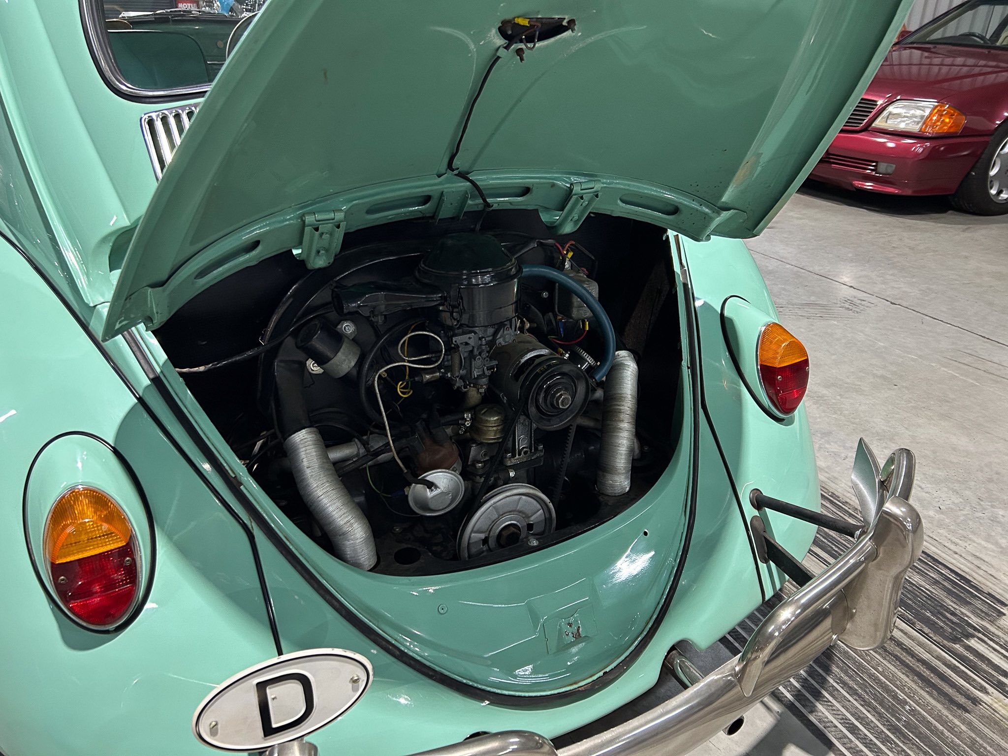 Mint green vintage car with hood open, showing its exposed engine and components in the engine bay.