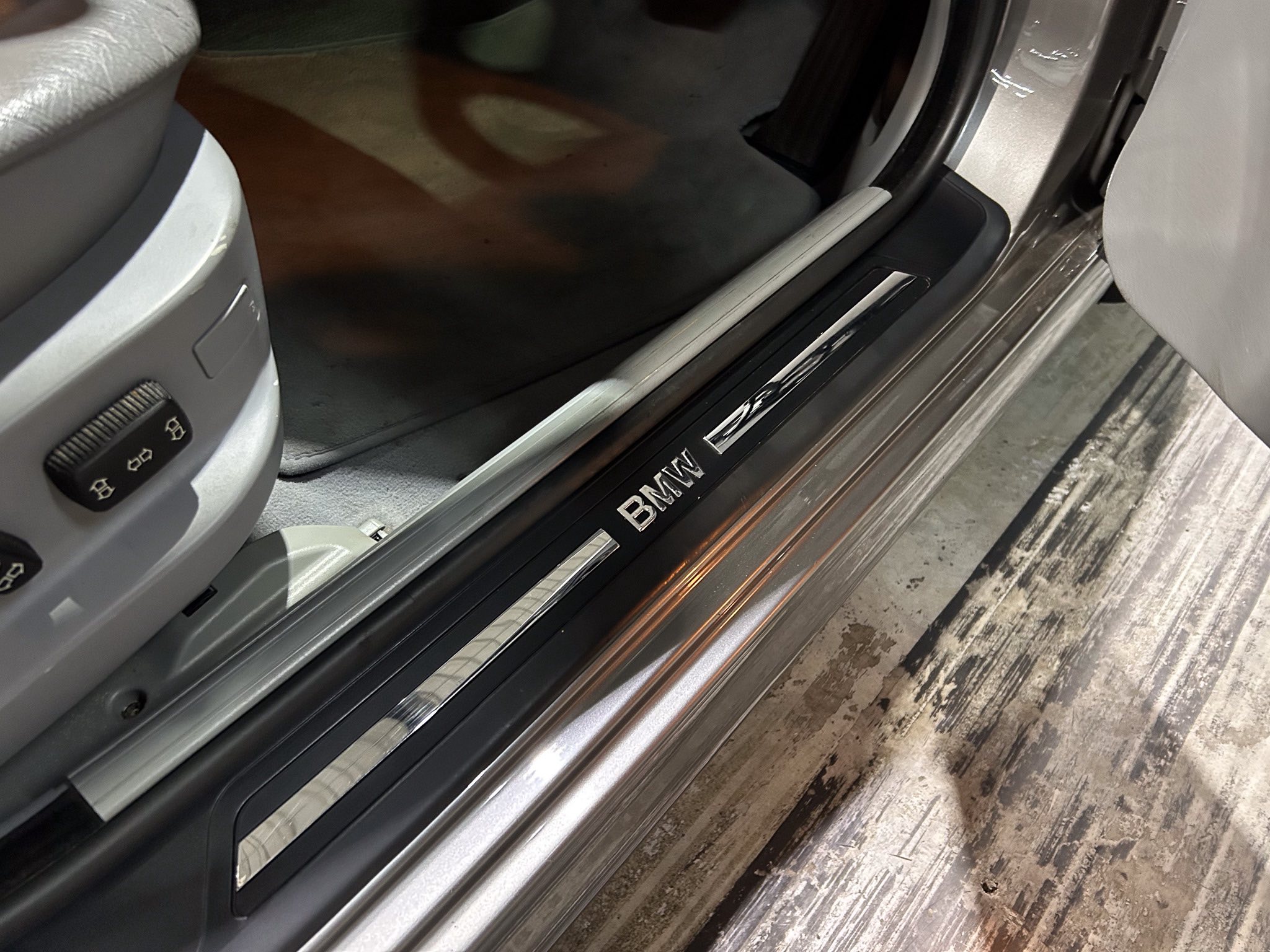 Close-up of a BMW car door sill with a brushed metal threshold and the BMW branding visible.