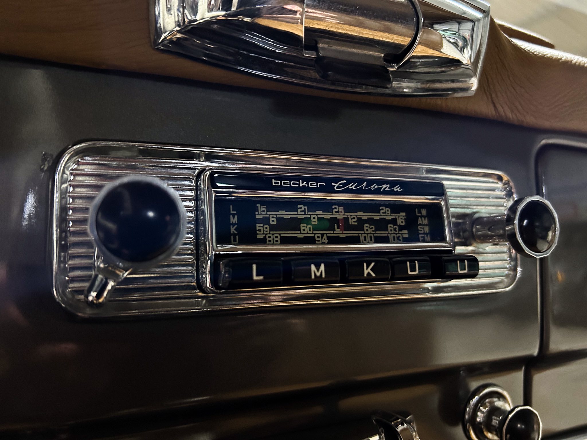 Close-up of a vintage car dashboard featuring a chrome Becker Europa radio with tuning dial.