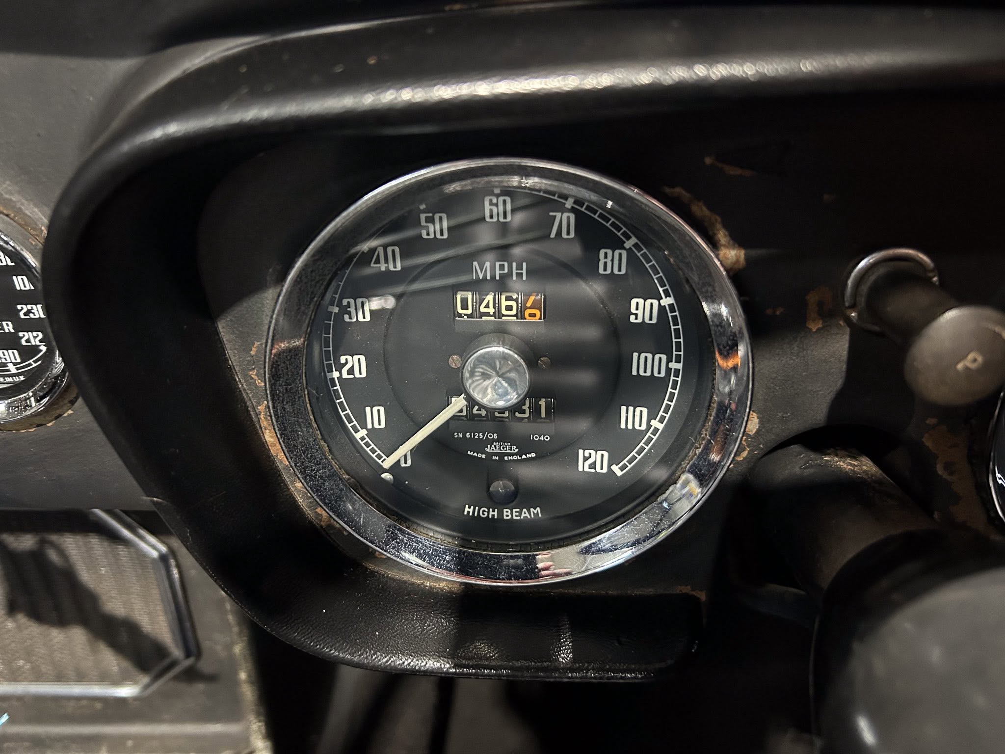 Close-up of a car speedometer reading up to 120 mph with an odometer showing a few miles and the 'HIGH BEAM' label visible at the bottom.