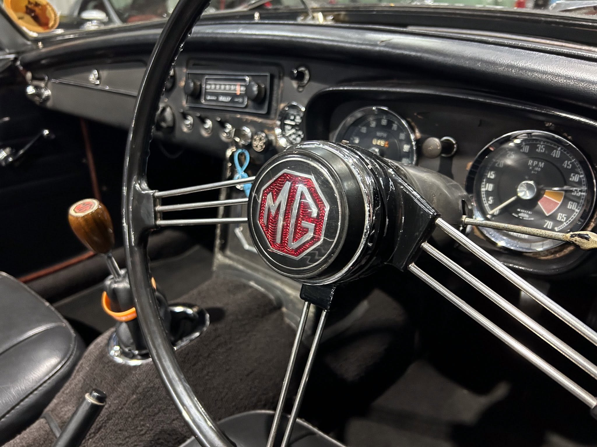 Close-up of a vintage car interior with an MG emblem on the steering wheel and analog gauges behind it