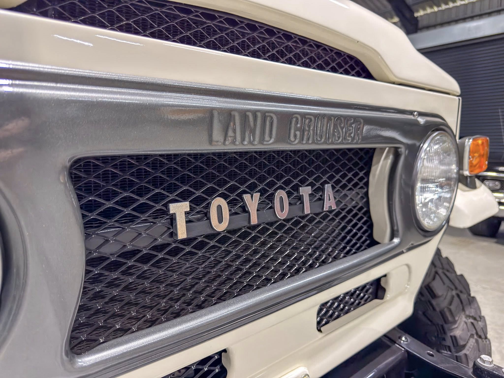 Close-up of the front grille on a Toyota Land Cruiser, with the embossed 'LAND CRUISER' badge.