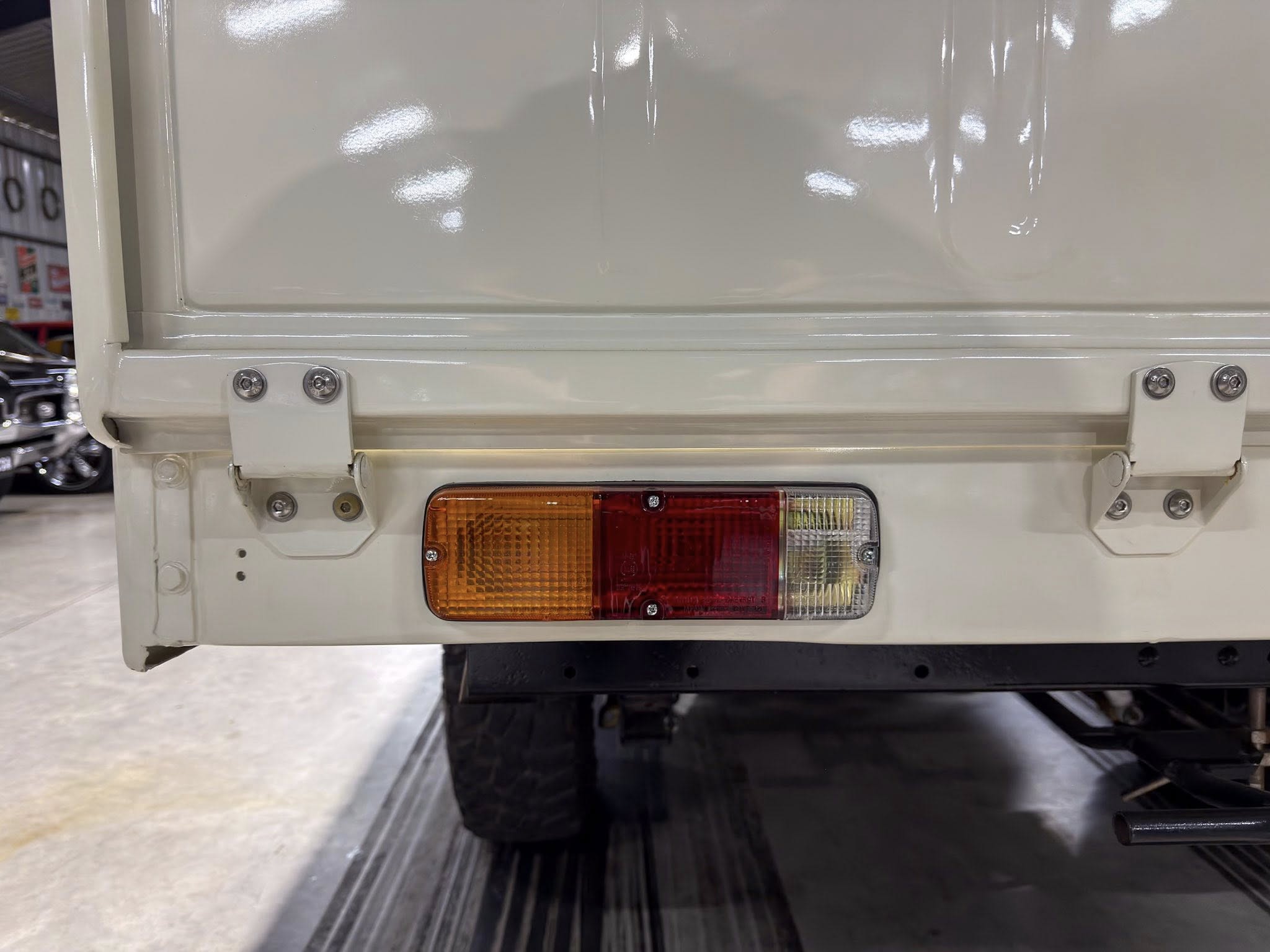 Rear view of a white utility truck showing tail light assembly and bumper in a showroom.