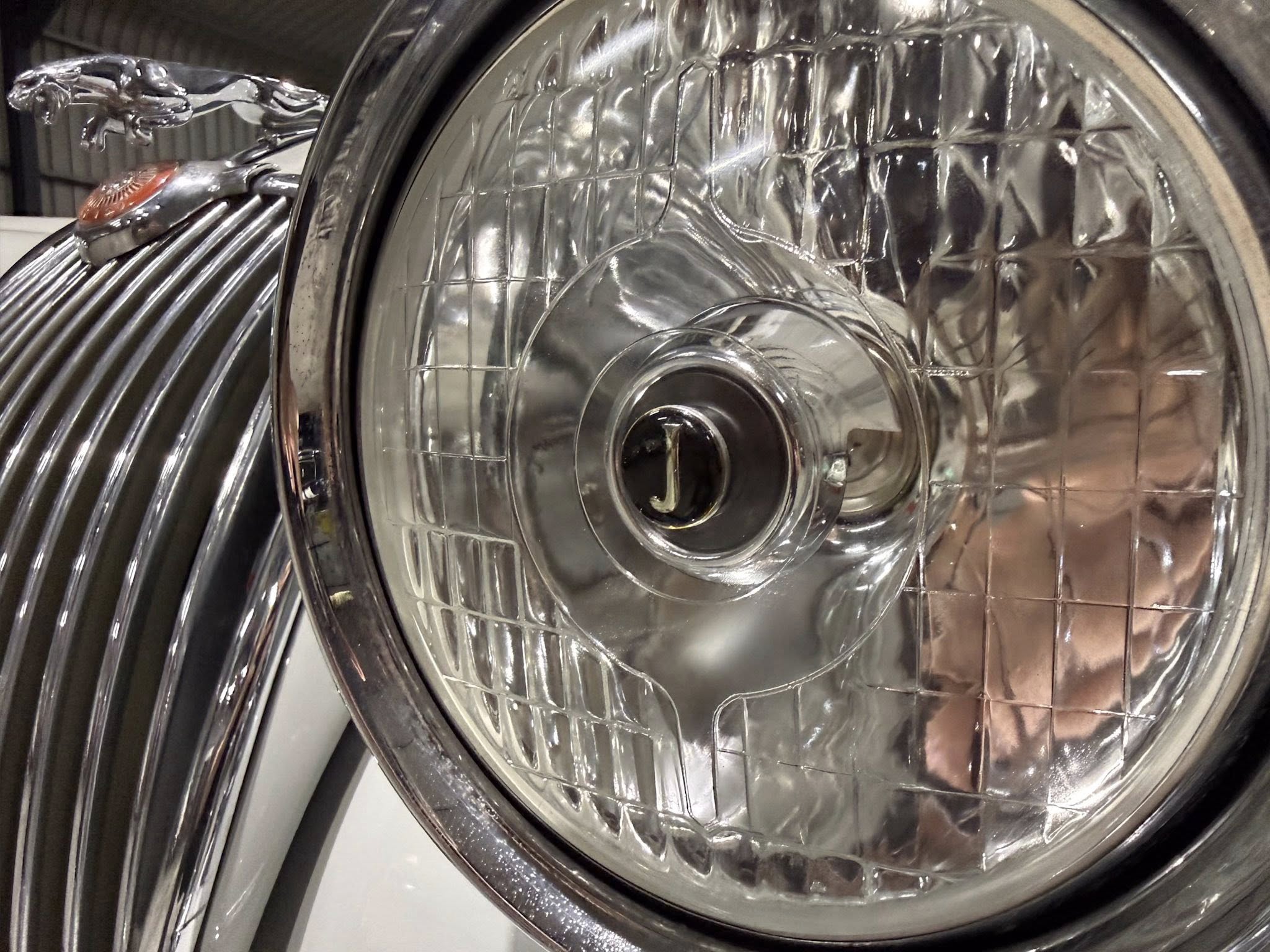 Close-up of a chrome car headlight with reflective inner housing and clear lens