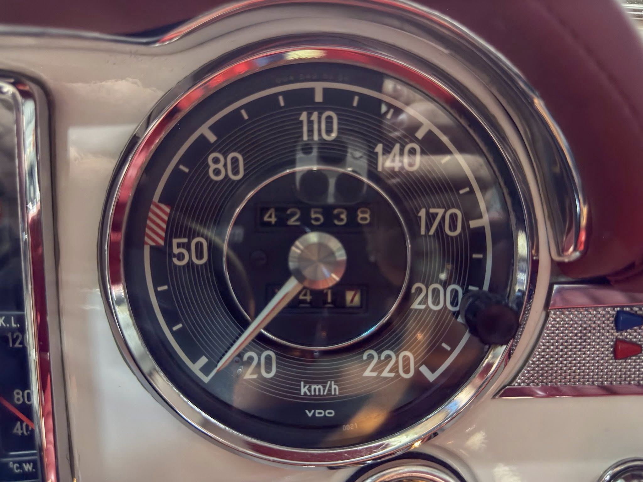 Close-up of a vintage car speedometer with a chrome bezel and a 0–220 km/h scale, showing the odometer reading 42538 near the bottom.
