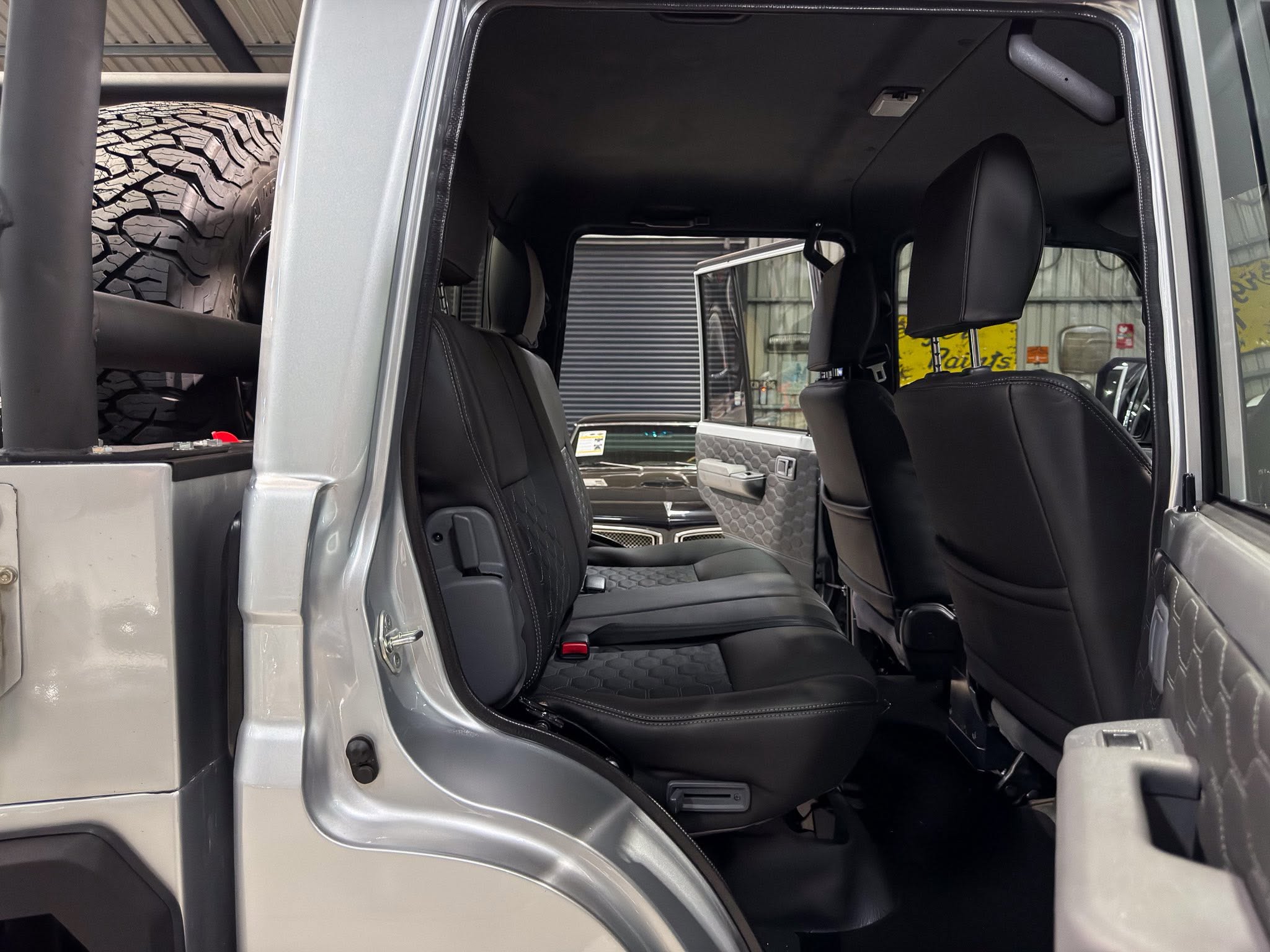 Interior of an SUV with a large spare tire visible in the rear cargo area, door open.