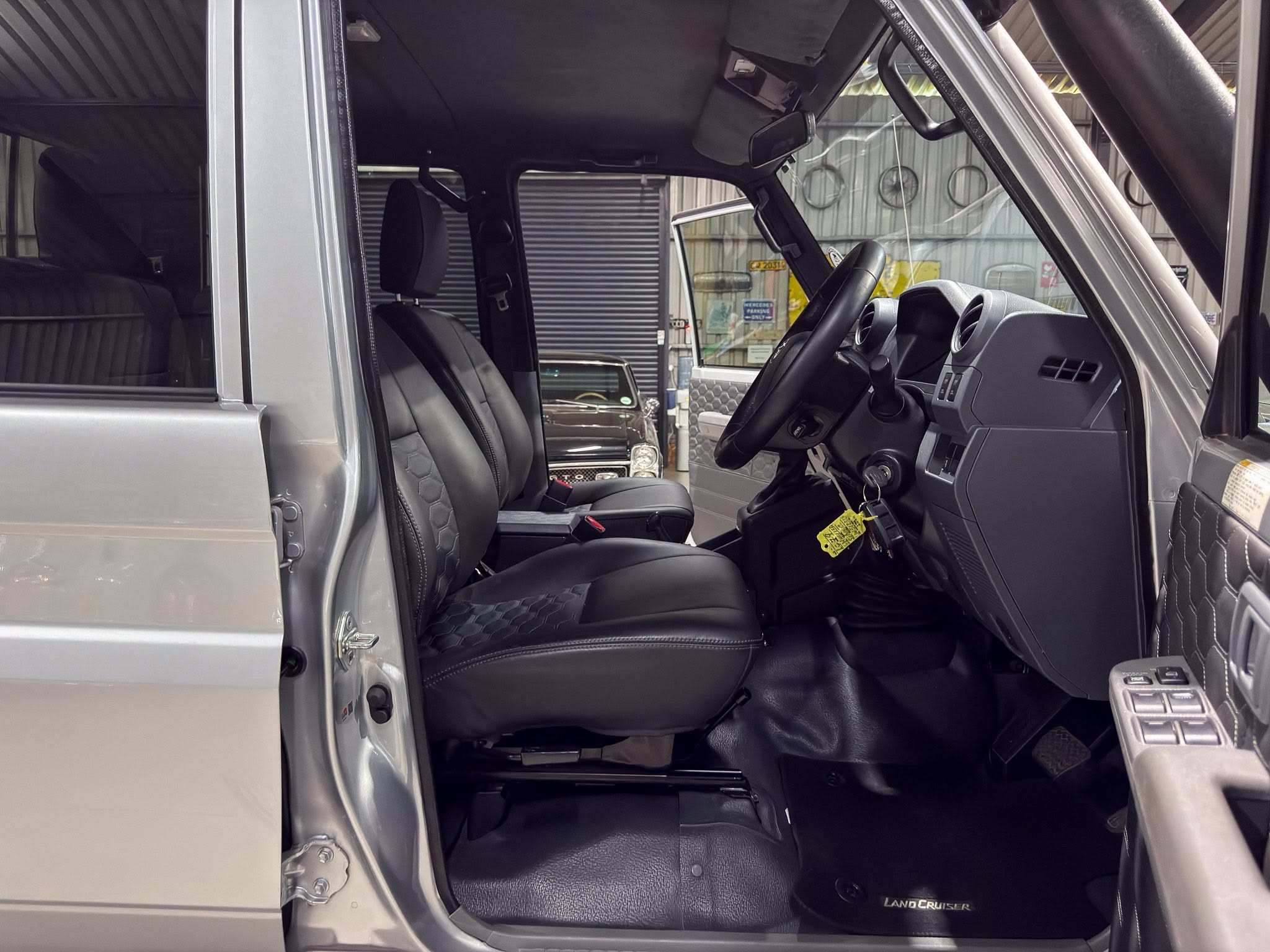 Open driver's door view of a gray SUV with black leather seats, dashboard, and steering wheel visible.