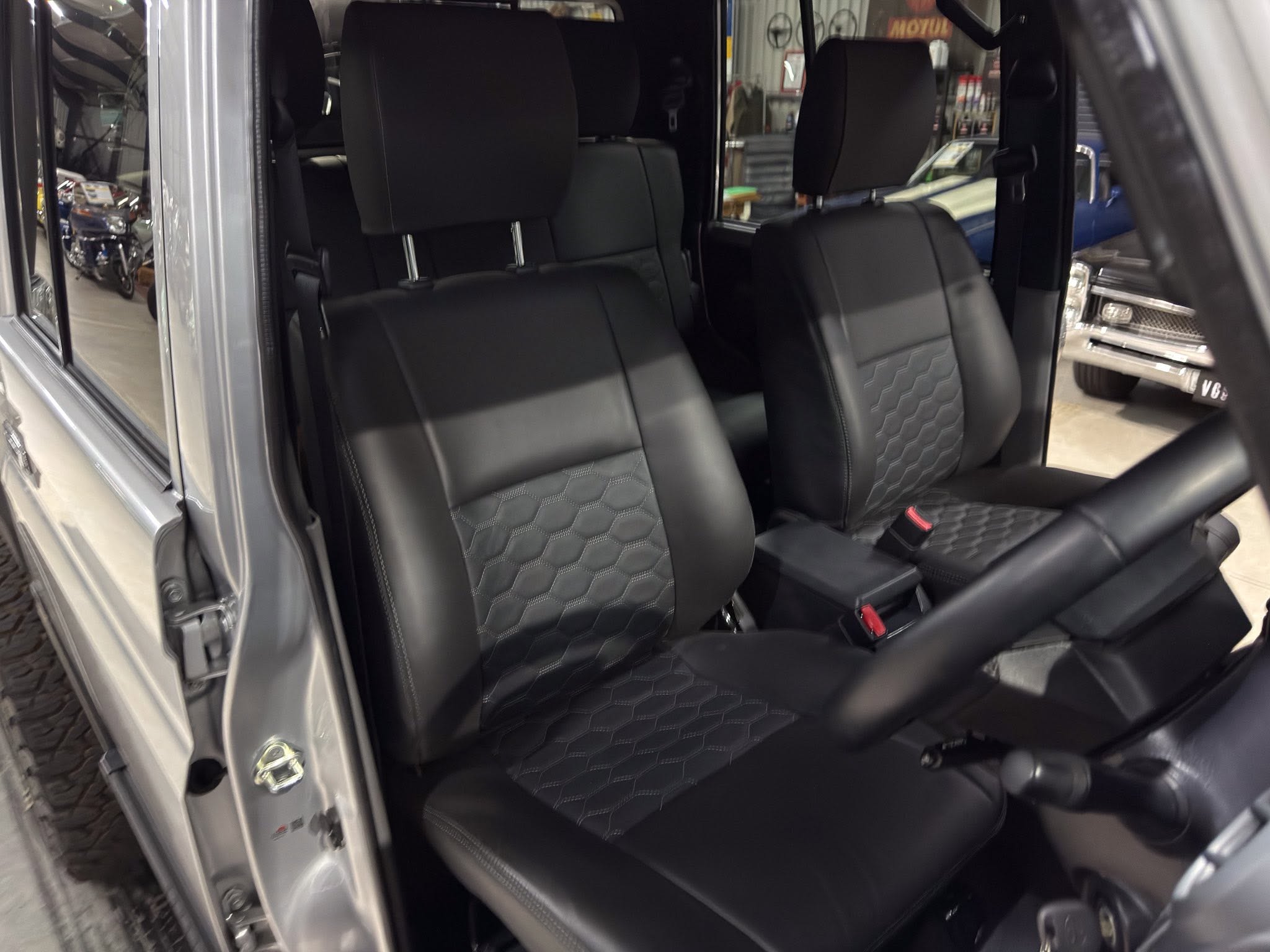 Interior of a black leather car with front and rear seats visible, passenger door open.