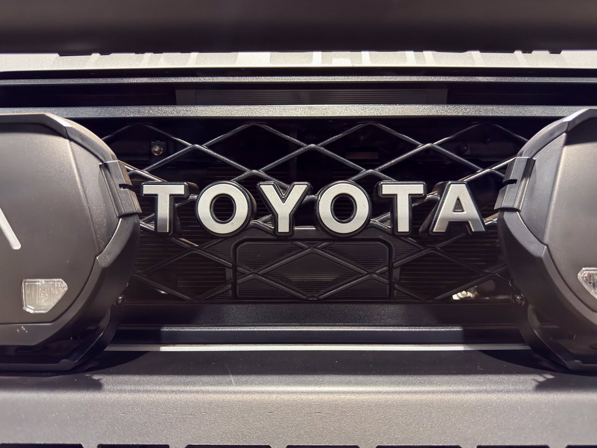 Close-up of a Toyota front grille with a diamond mesh pattern and the letters TOYOTA visible beneath