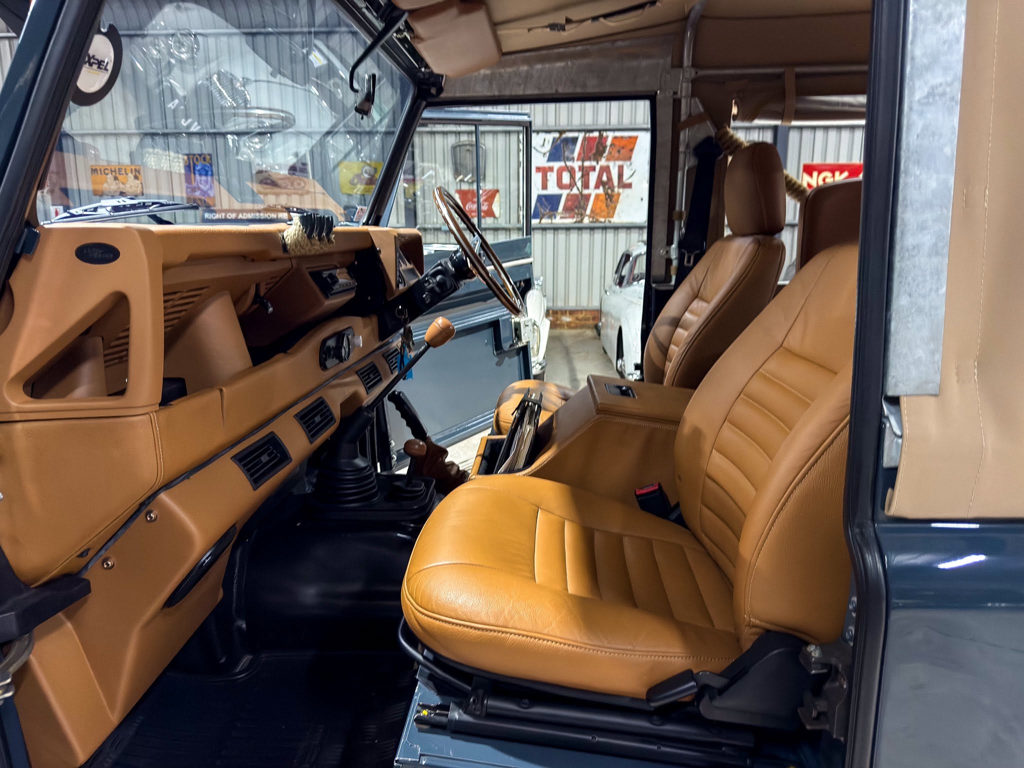 Front interior of a tan-leather SUV cabin, showing the steering wheel, dashboard, and driver seat.