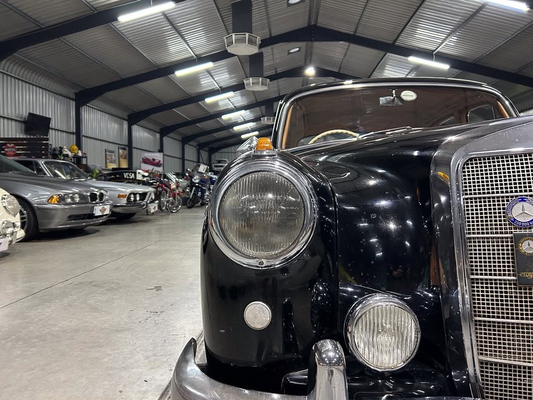 Front view of a black vintage car with large round headlight and chrome grille in a classic car showroom.