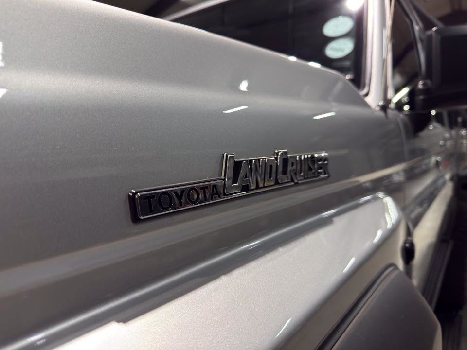 Close-up of the Toyota Land Cruiser badge on a silver SUV side panel.