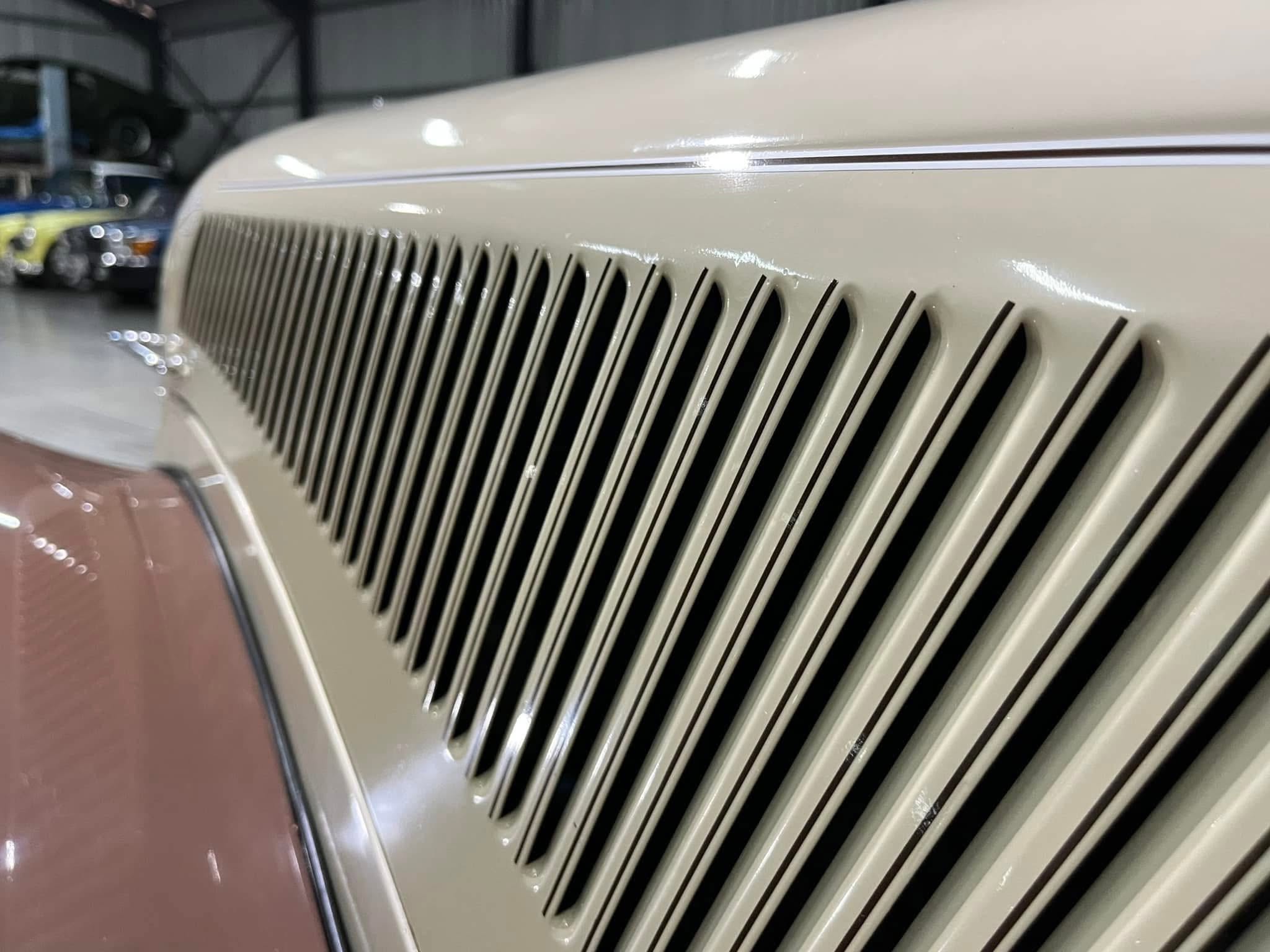 Close-up of a vintage car front with vertical chrome grille slats in a showroom setting