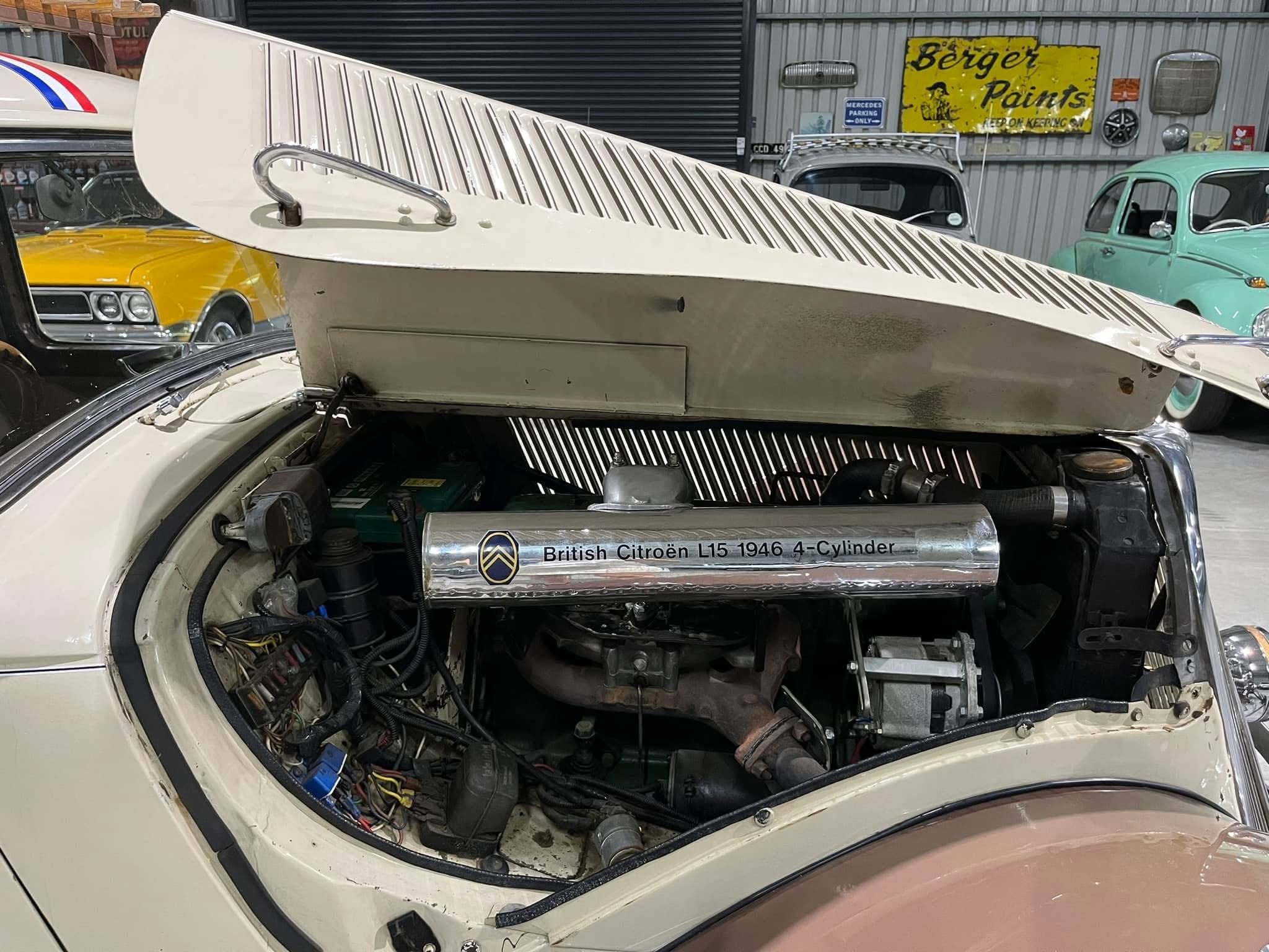 Open engine bay of a vintage car with a raised hood scoop and exposed wiring; chrome air intake labeled 'British Citroën L15 1946 4-Cylinder' visible inside.