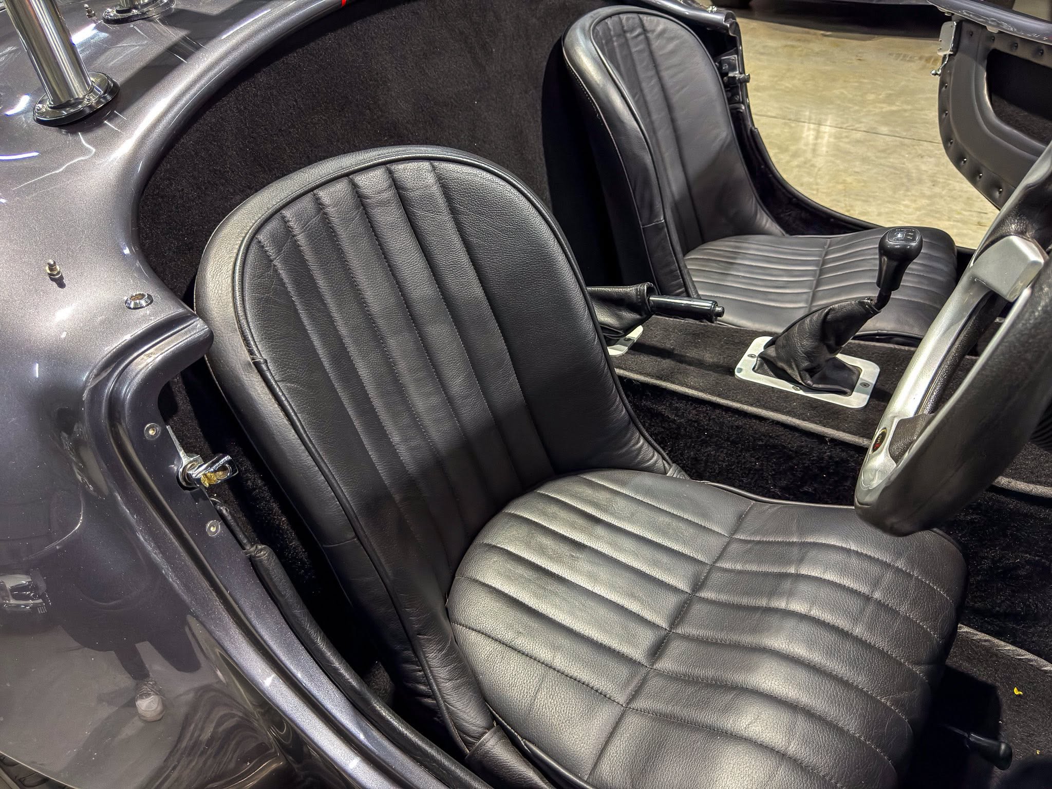 Interior of a black convertible showing two stitched leather seats and a manual gear shifter