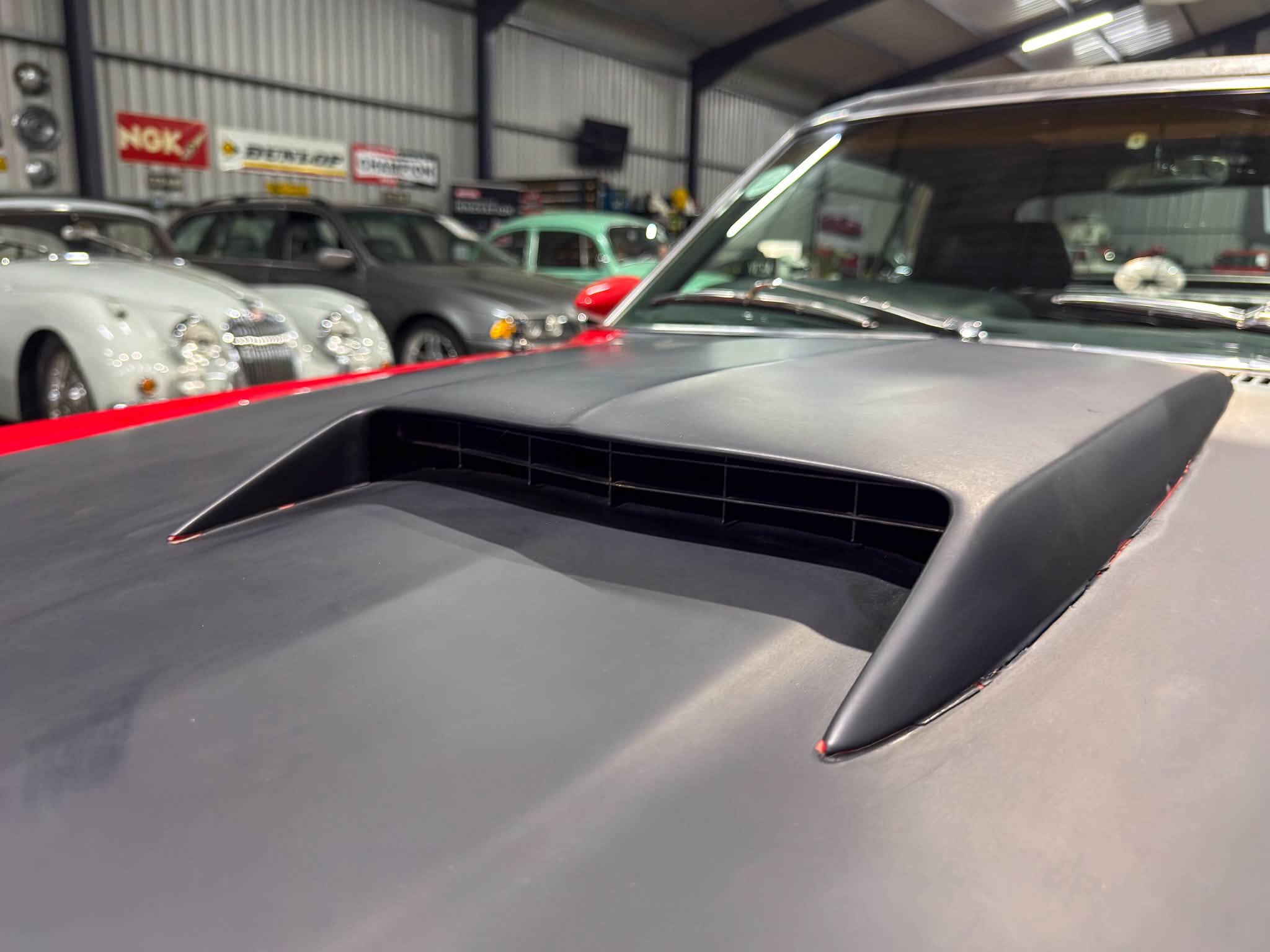 Interior view of a garage showroom filled with vintage classic cars lined up along the walls.