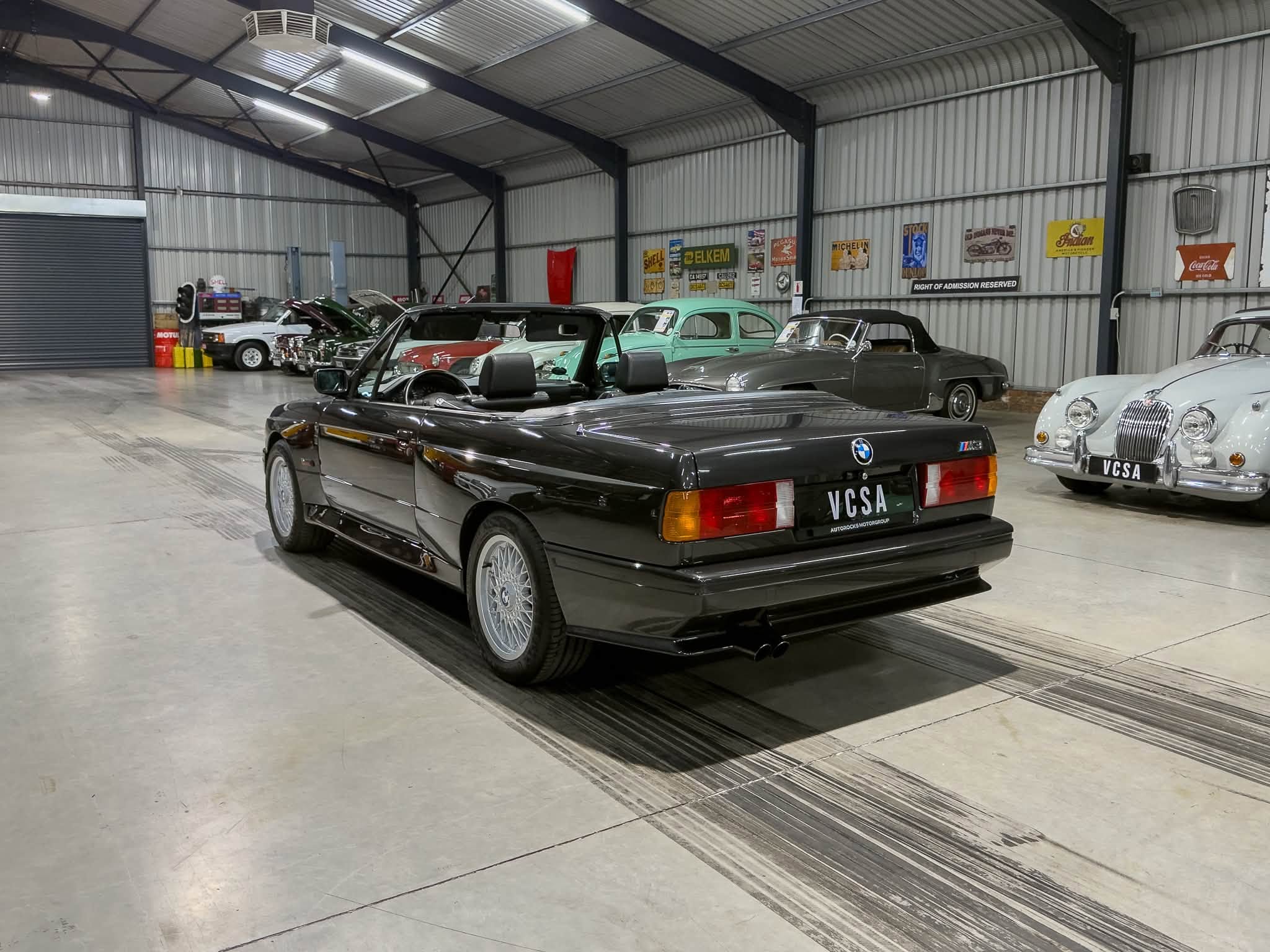 Indoor showroom with vintage convertibles and classic cars on display in a metal-walled garage