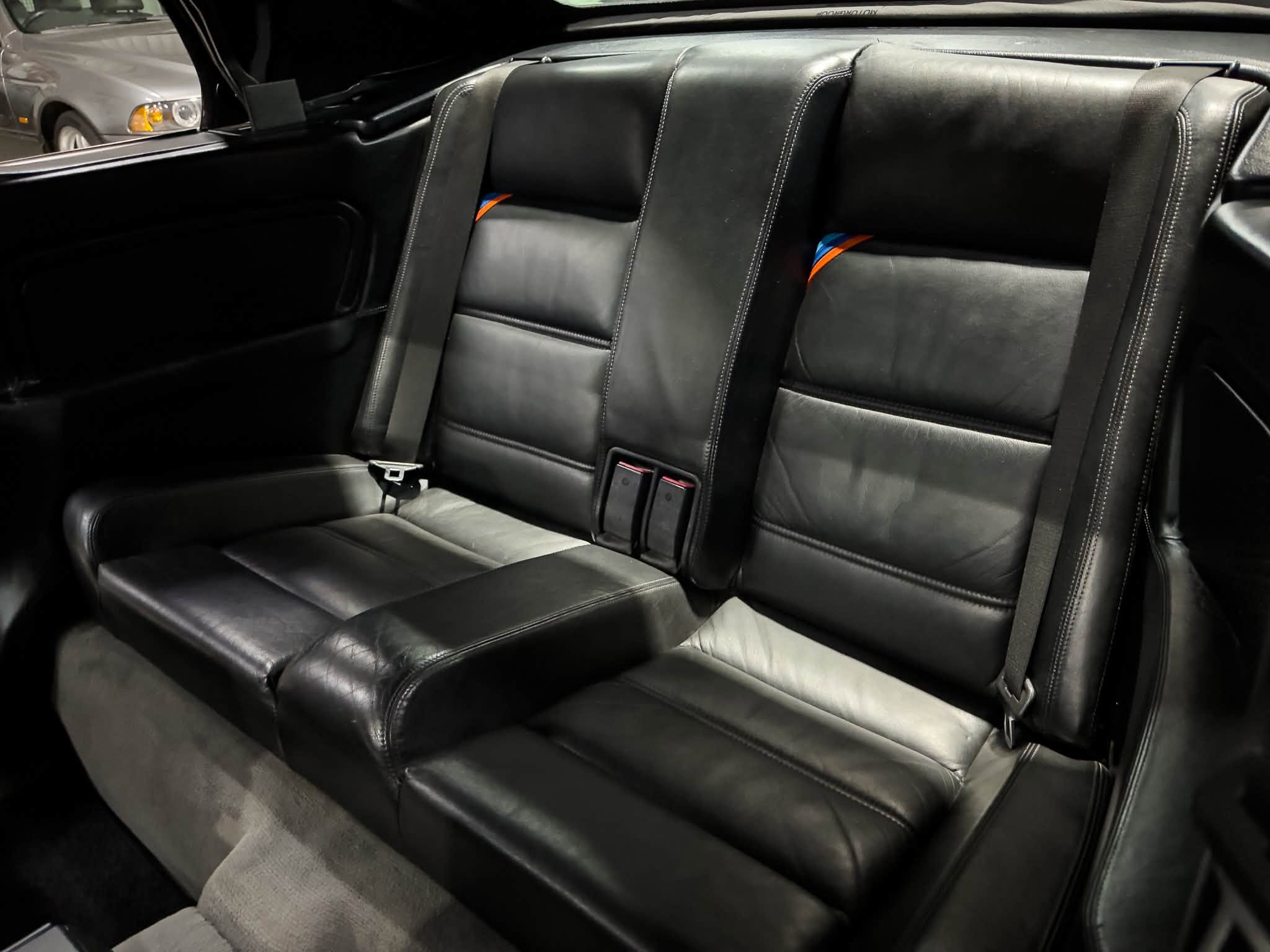 Two-tone black leather rear seats with visible seat belts in a car interior.